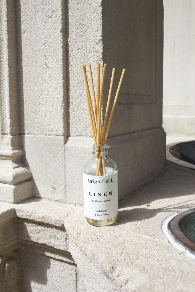 A natural reed diffuser from Brightfield with a white label. The scent is Linen which smells like lilac, lemon and jasmine.